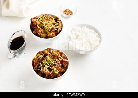 Würziges, gebratenes Huhn (Kkanpunggi) mit Knoblauch. Asiatisches Huhn in süßer und saurer Sauce auf weißem Hintergrund mit freiem Textraum. Stockfoto