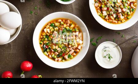 Traditionelle kalte russische Suppe Okroschka mit Wurst, Gemüse und Kvass über braunem Hintergrund. Leckeres Sommergericht zum Abendessen. Draufsicht, flacher Lay Stockfoto