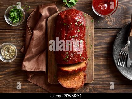 Hackbraten mit Glasur auf Schneidebrett auf Holzhintergrund. Draufsicht, flach liegend, Nahaufnahme Stockfoto