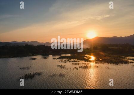 Luftaufnahme des Sonnenuntergangs über der Bergkette und dem Stausee in Landschaft bei Suphanburi Stockfoto