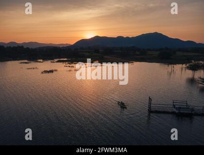 Luftaufnahme von Touristen, die im Kanu auf dem See paddeln Und Sonnenuntergang über den Bergen Stockfoto