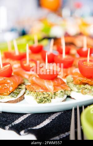 Kanapees mit rotem Fisch, Pesto und Kirschtomaten Stockfoto