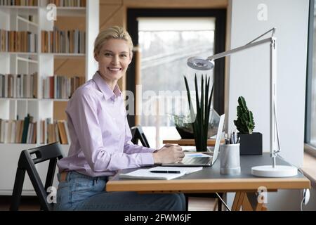 Porträt einer lächelnden erfolgreichen Geschäftsfrau, die im Büro am Schreibtisch sitzt Stockfoto