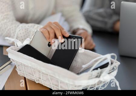 Nahaufnahme beschnittene Frau, die das Telefon in den Korb legte, kein Mobiltelefon Stockfoto
