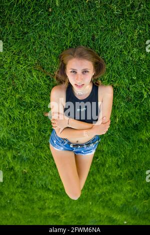 Junge Frau, die auf dem Universitätsgelände auf Gras liegt Stockfoto