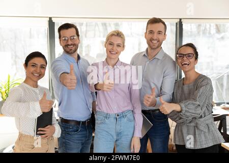 Porträt eines erfolgreichen Teams verschiedener Mitarbeiter mit Daumen nach oben Stockfoto