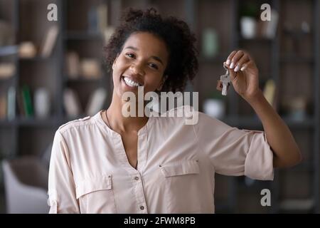 Junge aufrichtige afroamerikanische Frau zeigt Schlüssel zur Kamera. Stockfoto