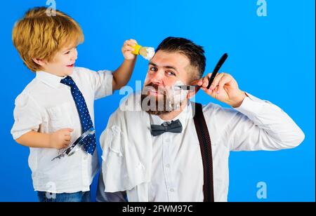Vatertag. Assistent für Papa. Sohn und Vater rasieren sich den Bart. Bartpflege. Kleiner Barbier. Barbershop-Konzept. Stockfoto