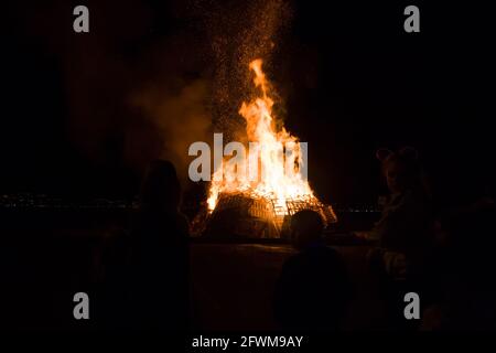 Silhouette von Jungen und Mädchen, die ein Lagerfeuer beobachten. Stockfoto