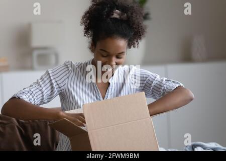 Glückliche tausendjährige afroamerikanische Frau Auspacken Paket. Stockfoto