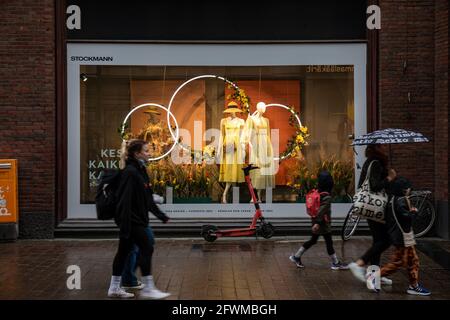 Menschen, die an einem regnerischen Tag im finnischen Helsinki am Stockmann Kaufhausfenster vorbeikommen und Sommerkleidung zeigen Stockfoto