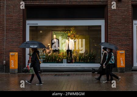 Menschen mit Regenschirmen, die am Stockmann Kaufhausfenster vorbeikommen, zeigen an einem regnerischen Tag in Helsinki, Finnland, markierte Sommerkleidung Stockfoto