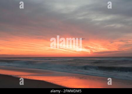 Die Momente vor dem Sonnenaufgang sind in wunderschönen rosa Farbtönen überflutet, die sich im Ozean widerspiegeln. Stockfoto