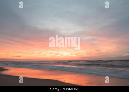 Die Momente vor dem Sonnenaufgang sind in wunderschönen rosa Farbtönen überflutet, die sich im Ozean widerspiegeln. Stockfoto