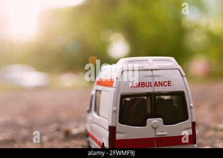 Ambulanzwagen auf dem Asphalt unter den Bäumen im Sonnenlicht Stockfoto