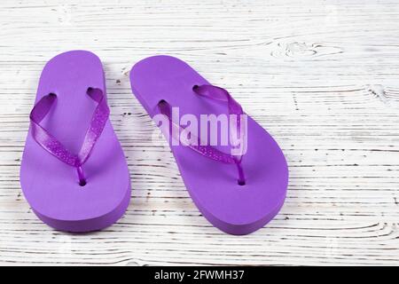 Lila Flip-Flops aus Gummi auf weißem Holzhintergrund Stockfoto