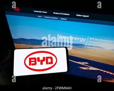 Person, die das Smartphone mit dem Logo des chinesischen Automobilherstellers BYD Co. Ltd. Auf dem Bildschirm vor der Business-Webseite hält. Konzentrieren Sie sich auf die Anzeige des Mobiltelefons. Stockfoto