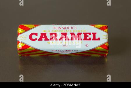 Tunnock's Milk Chocolate Coated Caramel Wafer Biscuit 30g Bar auf dunkelbraunem Hintergrund Stockfoto
