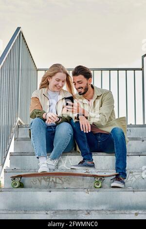 Junge multirassische Paar lächelt, während sie auf ein schauen Telefon Stockfoto