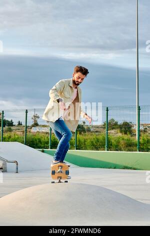 Der junge Mann skates in legerer Kleidung in einem Skatepark Stockfoto