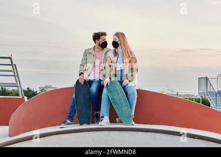 Junge Paare in Masken sehen sich in einem an Skatepark Stockfoto