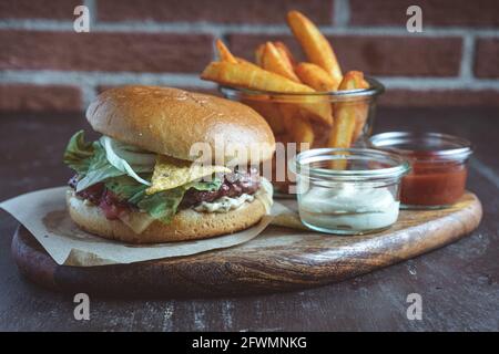 Nahaufnahme eines Hamburgers mit Nachos und pommes Frites Holzbrett Stockfoto