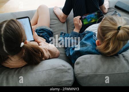 Zwei Geschwister sitzen auf der Couch und beobachten ihre Telefone nebeneinander Stockfoto