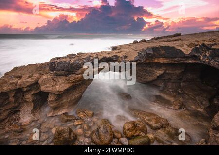 Bogenförmige Felsformation in der Küste bei Sonnenuntergang. Stockfoto