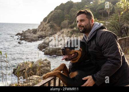 Mann, der mit seinem rottweiler Hund den Meerblick genießt Stockfoto