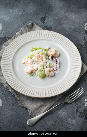 Salat mit Garnelen, Avocado, Tomaten und Mayonnaise auf dem Salat-Set, mit Sauce Apfel und Traube, auf grauem Hintergrund Stockfoto