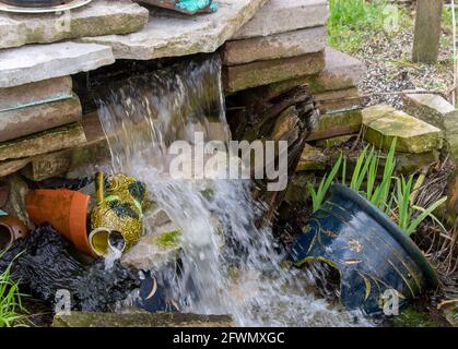 Der Wasserfall im Garten ist mit zerbrochenen Töpferwaren dekoriert. Stockfoto