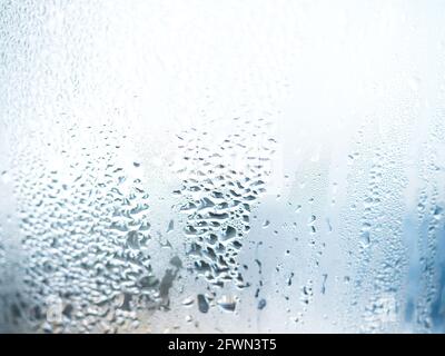 Nahaufnahme Natur Wassertropfen Textur auf Glas mit verschwommenem blauen Hintergrund. Feuchtigkeit der Luft, die Dampf auf dem Glas verursacht. Stockfoto