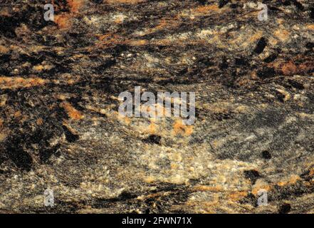 Ein Fragment aus schwarzem Marmor mit weißen und orangen Flecken und Adern, Nahaufnahme. Hintergrund, Muster, Textur. Stockfoto