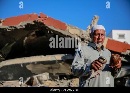 Gaza, Palästina. Mai 2021. Nazmy al-Dahdouh, ein 70-jähriger Palästinenser, spielt mit seinen Vögeln über den Ruinen seines Hauses, das kürzlich bei israelischen Luftangriffen in Gaza-Stadt zerstört wurde.die Bewohner des Gazastreifens versuchten, ihr Leben zurückzugeben, Nach einem verheerenden 11-tägigen Konflikt mit Israel, bei dem mehr als 200 Menschen getötet und Tausende in der verarmten palästinensischen Enklave obdachlos gemacht wurden. (Foto von Ahmed Zakot/SOPA Images/Sipa USA) Quelle: SIPA USA/Alamy Live News Stockfoto