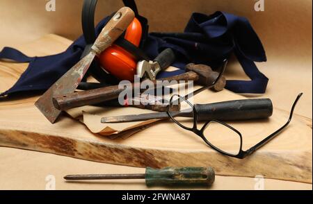 Eine Anordnung von gut abgenutzten Bauwerkzeugen auf einer geschliffenen Holzrunde. Zimmerei manuelle Kunst Handel Stil Objekte auf einem braunen Hintergrund. Stockfoto