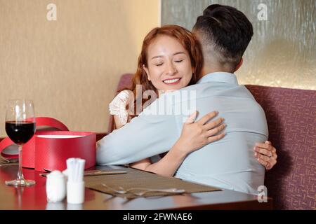 Glückliche hübsche junge Frau umarmte ihren Freund nach dem Geburtstag Anwesend Stockfoto
