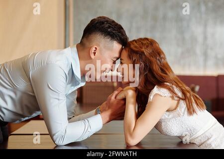 Glücklicher junger Mann in der Liebe hält die Hände der Freundin und Sie schaute in ihre Augen Stockfoto