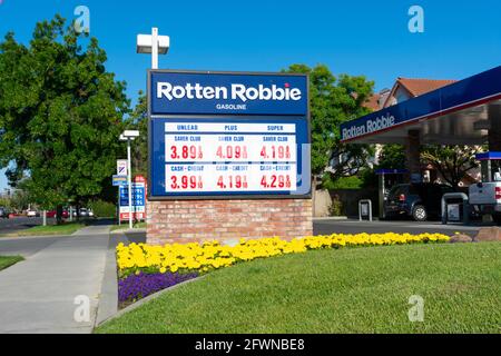Aktuelle Gaspreise werden auf blauem Schild angezeigt. Außenansicht der verfaulten Robbie-Tankstelle. - San Jose, Kalifornien, USA - Mai 2021 Stockfoto