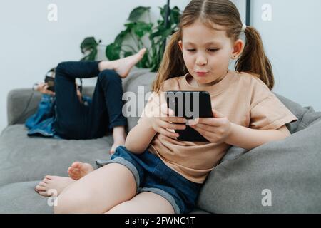 Unterhielt Mädchen mit zwei Pony Schwanz beobachtete ihr Telefon an Ein Sofa Stockfoto