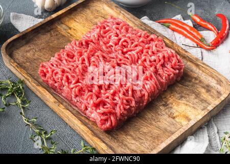 Rohe Fleischbällchen aus gemahlenen Rindfleischzutaten auf grauem Steingrund Stockfoto