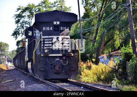 Chicago, Illinois, USA. Eine Norfolk Southern Diesellokomotive parkt auf einer Nebenbahn die zwischen und parallel zu zwei Wohnblöcken verläuft Stockfoto