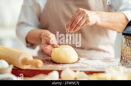 Nahaufnahme des Bäckers funktioniert. Hausgemachtes Brot. Hände, die Teig auf Holztisch vorbereiten. Stockfoto