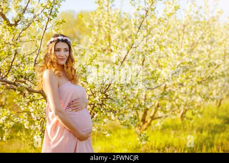 Schwangerschaft Frau im Frühling blühenden Garten. Schöne schwanger Mädchen Stockfoto