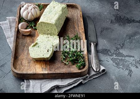 Portion Kräuterbutter mit Schnittlauch, Basilikum, Oregano, Petersilie-Set, auf grauem Steinhintergrund, mit Platz für Text Stockfoto