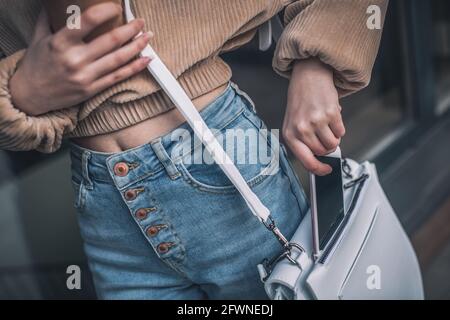 Nahaufnahme einer Frau, die ihr ein Smartphone zulegt Tasche Stockfoto
