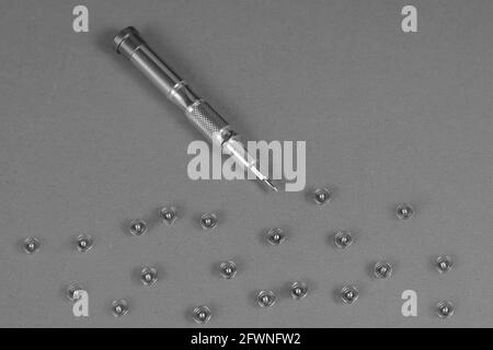 Computer-Reparatur-Dienstleistungen und Komponenten-Konzept. Schrauben und Schraubendreher aus einem Computer herausgeschraubt. Nahaufnahme, selektiver Fokus. Monochrom Stockfoto