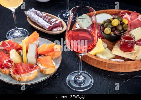 Roséwein und italienische Antipasti oder spanische Tapas in einer Bar. Blauschimmelkäse, Schinken aus Parmaschinken, Jamon, Oliven und Samon-Sandwiches Stockfoto