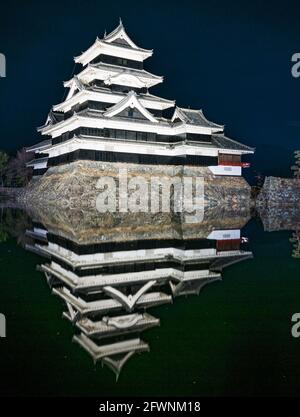 Schloß Matsumoto mit seiner Reflexion in den Graben in der Nacht gesehen. Der Präfektur Nagano auf der Insel Honshu, Japan. Stockfoto