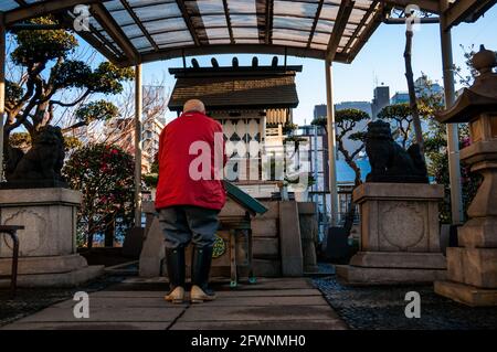 Ein älterer Ladenbesitzer betet am Namiyoke-Jinja, einem Shinto-Schrein in einer ruhigen Ecke des Tsukiji Fischmarktes in Tokio. Stockfoto