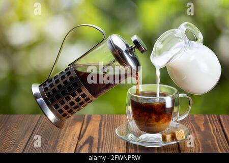 Kaffee und Rahm werden in eine Glastasse gegossen Stockfoto